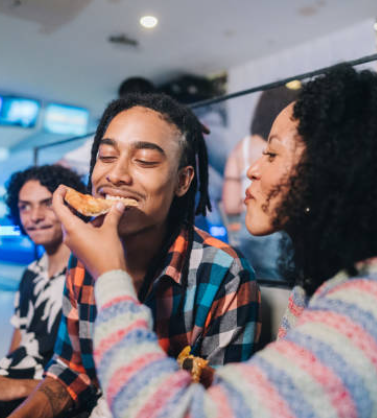 Young woman giving pizza to her friend at a bowling club